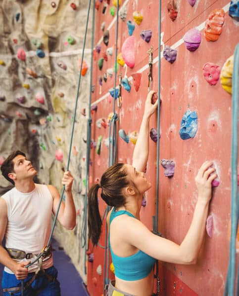 Frau klettert Kletter-Wand hoch und ein Guide sichert sie beim Klettern und Bouldern in Saarbrücken