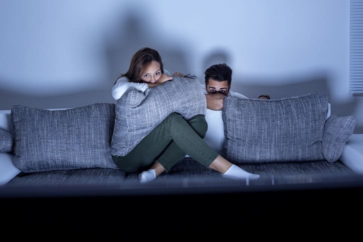 Sie und Er verstecken sich hinter dem Sofa